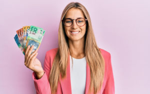 Ways to make money - Woman holding up Australian bank notes smiling
